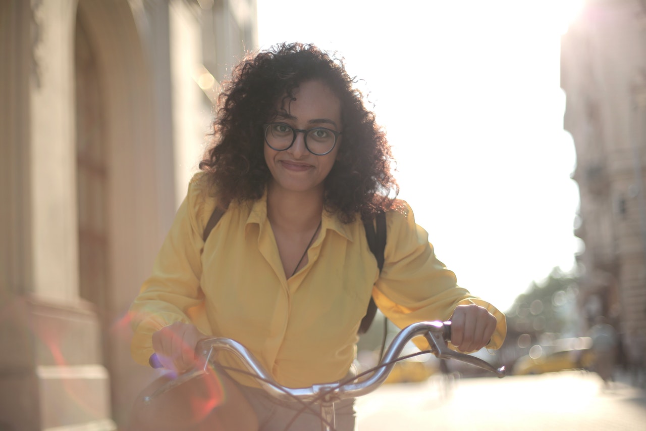 Glückliche weibliche Reisende mit Fahrrad auf der Straße in der Innenstadt